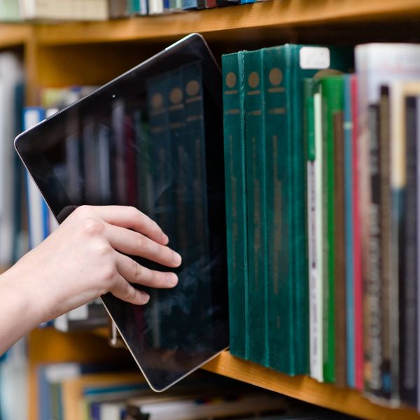 Taking an IPad from a shelf of books