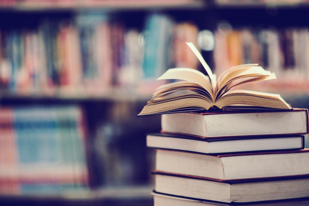 Pile of Library books with blurred bookshelves in background