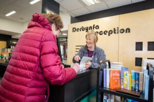 Library user checking out a book at library reception counter